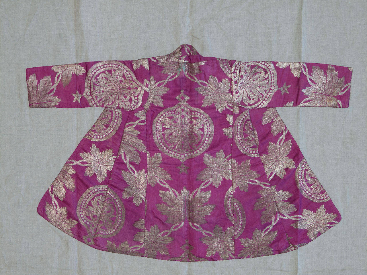 A luxurious coat for a child, from Uzbekistan in Central Asia. Metal thread (gold or silver) brocading on silk, a technique and style favored among the urban classes in Bukhara, Samarkand, etc. in the 19th century.

Mounted on linen, ready for