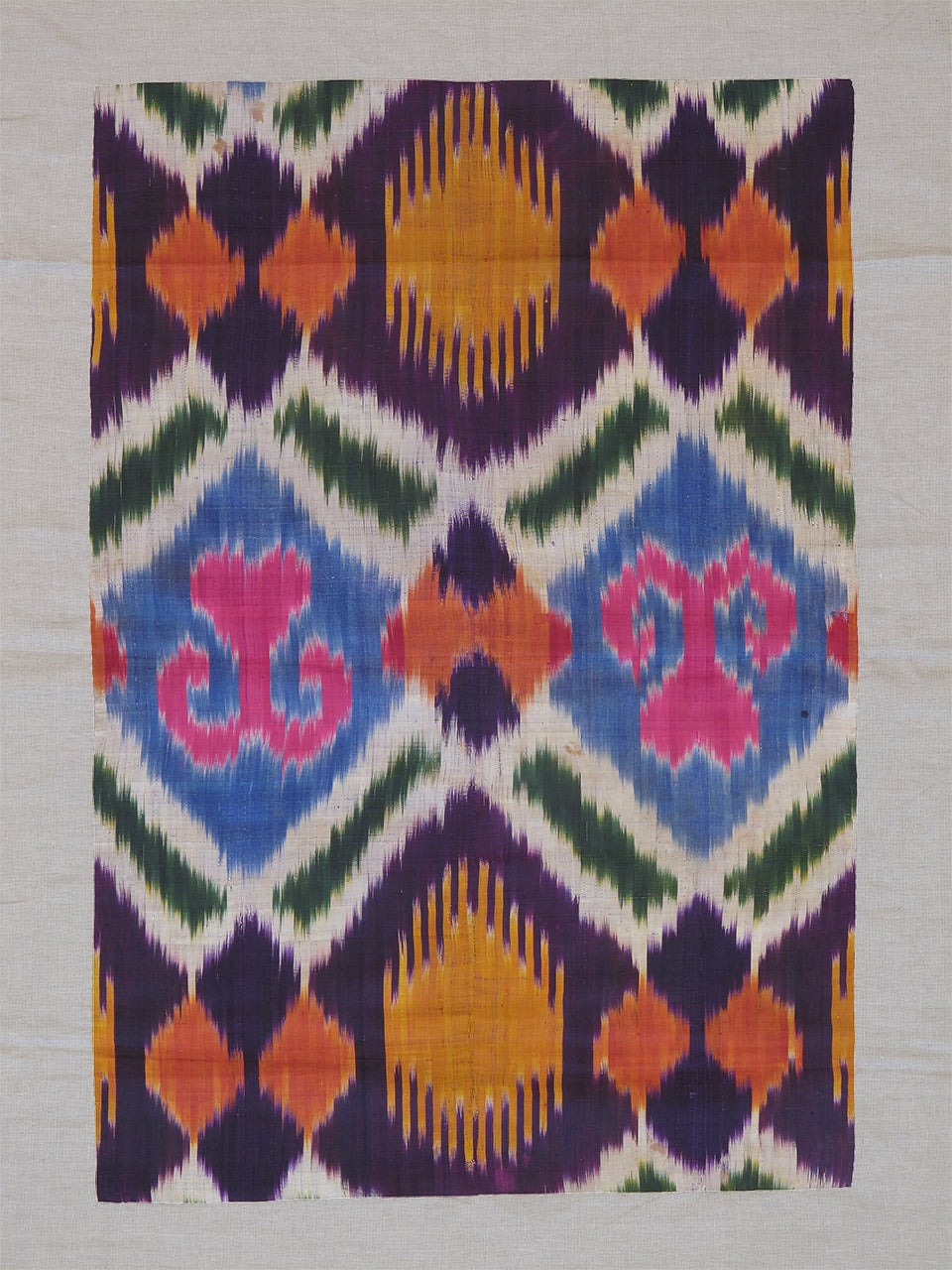 A beautiful antique textile from Uzbekistan in Central Asia, a fragment from a larger panel woven in silk ikat technique. Such fabrics were traditionally used to make garments or as ceremonial covers.

The piece is professionally mounted on linen