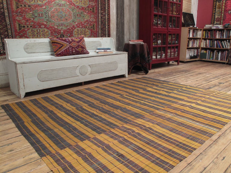 Banded cover rug in three panels. A simple flat-weave rug, woven in panels on a narrow loom. The variation in the spacing of the stripes and random use of color is very pleasing. Rug can be used on the floor in low traffic; can also be an