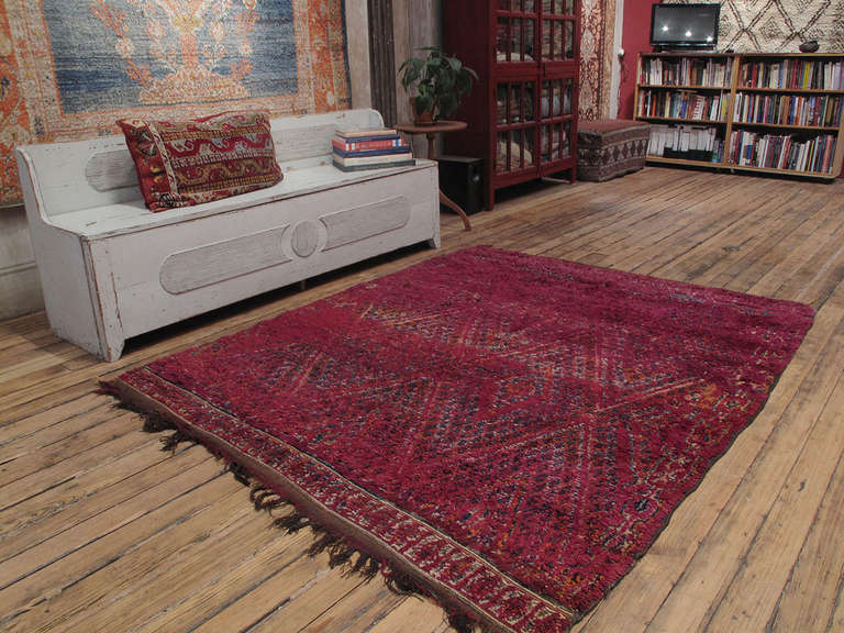 A great old Moroccan Berber rug, woven by the Beni Mguild tribes of the Middle Atlas Mountains. An earlier example featuring a well-known design type in richly saturated tones of red, purple and orange. The square-ish size is unusual as these are