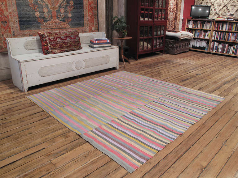 Colorful striped cover rug. A lovely old flat-woven cover rug from Turkey, woven in narrow panels on a home loom, with light and cheerful colors. It would make a great bedspread, a table cloth or even on the floor as a rug in a low traffic spot.