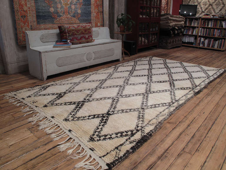 An old Moroccan Berber rug by the Beni Ouarain tribes of the Middle Atlas Mountains, who used these large rugs as beds in their tents and cottages.

The classic diamond grid design is framed by a zigzag border. The wool has a nice sheen as is