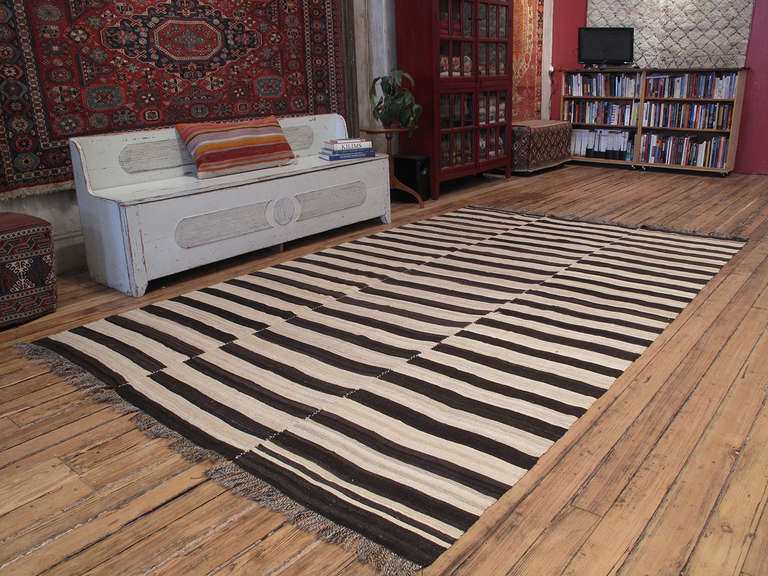 An old tribal floor cover from Iran, woven in three panels, with alternating bands of un-dyed wool in dark brown/black and ivory tones. A strikingly modern look, with great texture and patina that cannot be replicated in contemporary weavings.