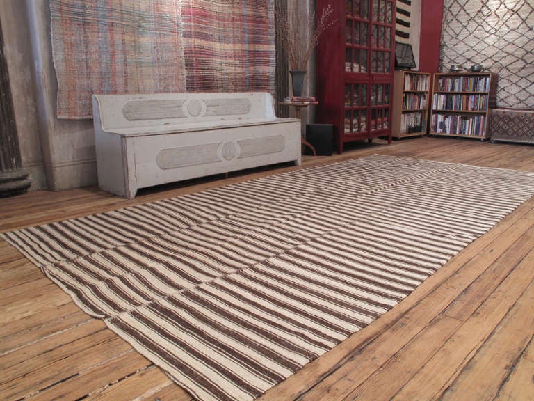 An old tribal floor cover from Iran, woven in three panels, with alternating bands of un-dyed wool in dark brown and ivory tones. A strikingly modern look, with great texture and patina.