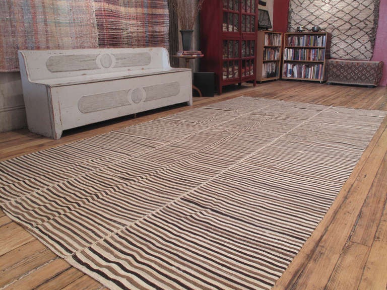 A simple tribal floor cover, woven in three narrow panels, with alternating stripes of naturally colored wool in three different tones. A very nice example of this type.