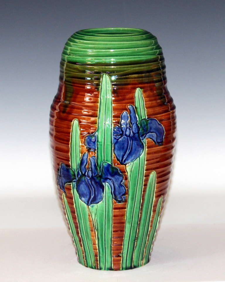 Awaji Pottery vase with blooming irises carved into accentuated throw ribs. The blue and green irises set aglow against the warm brown ground. Measures: 12 1/2