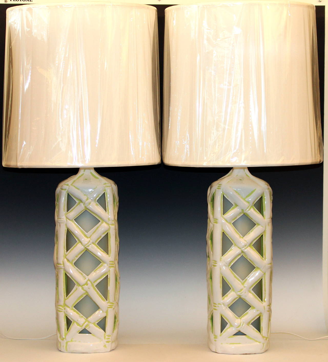 Large pair of vintage faux bamboo art pottery lamps in white with green highlights, circa 1960's. With interior night lanterns that show off the bamboo lattice bungalow tiki hut design.  3-way main light and separate switch for lantern at base. 37