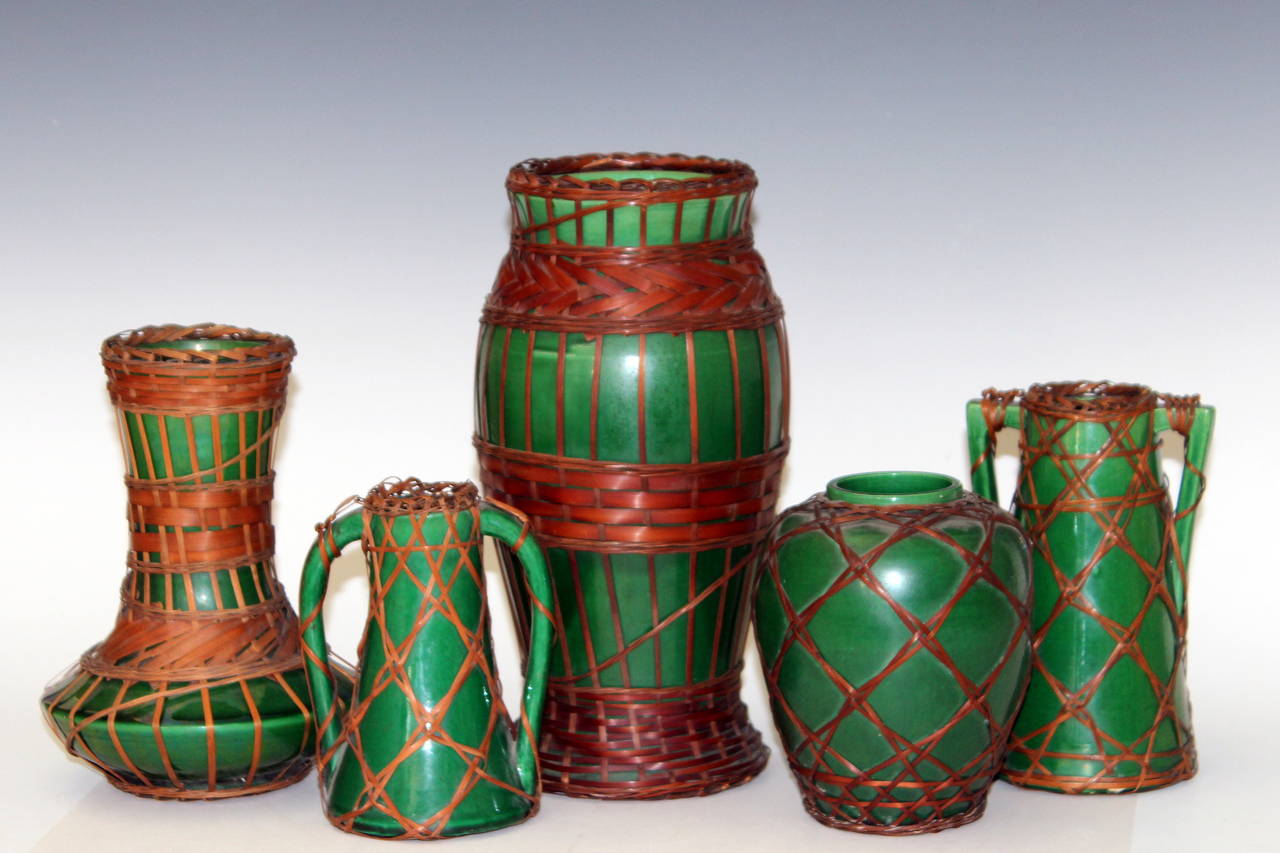 Collection of five Awaji pottery pieces with split bamboo weaving over deep green glaze. Circa 1910-1920. Approximately 5-10 inches high. Impressed marks. Good condition, bamboo with several breaks and brittleness.