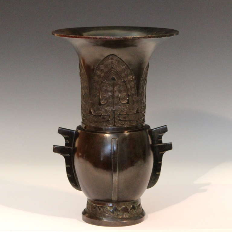 Antique Japanese bronze Archaic style Yen Yen form vase, circa early 20th century. With wide everted mouthrim above four large lappets each with Archaic taotie designs on a leiwen ground. The body with protruding handles/flanges and flared foot.