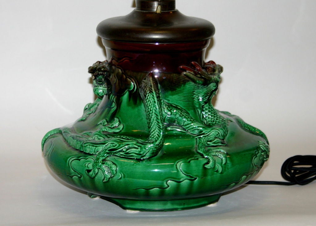 Japanese Awaji pottery lamp converted to electricity from kerosene. Pair dragons in high relief circling shoulder of lamp. Dramatic aubergine and green glaze.