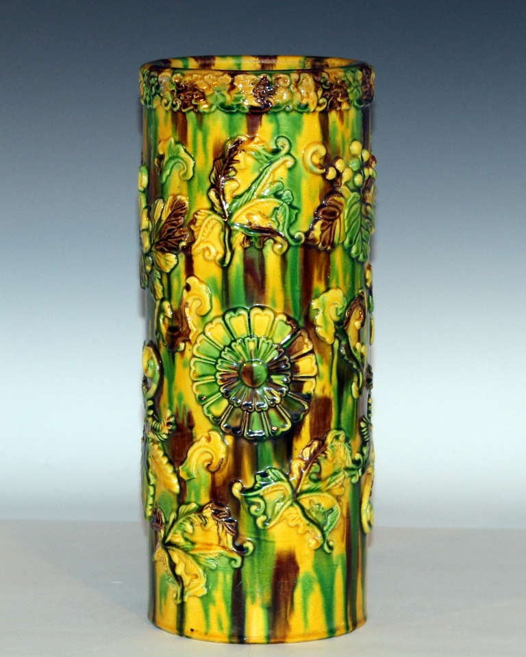 Large cylindrical Awaji pottery brush pot or vase in sancai (three color) glaze over applied chrysanthemums and foliage, circa 1900. Measures: 13