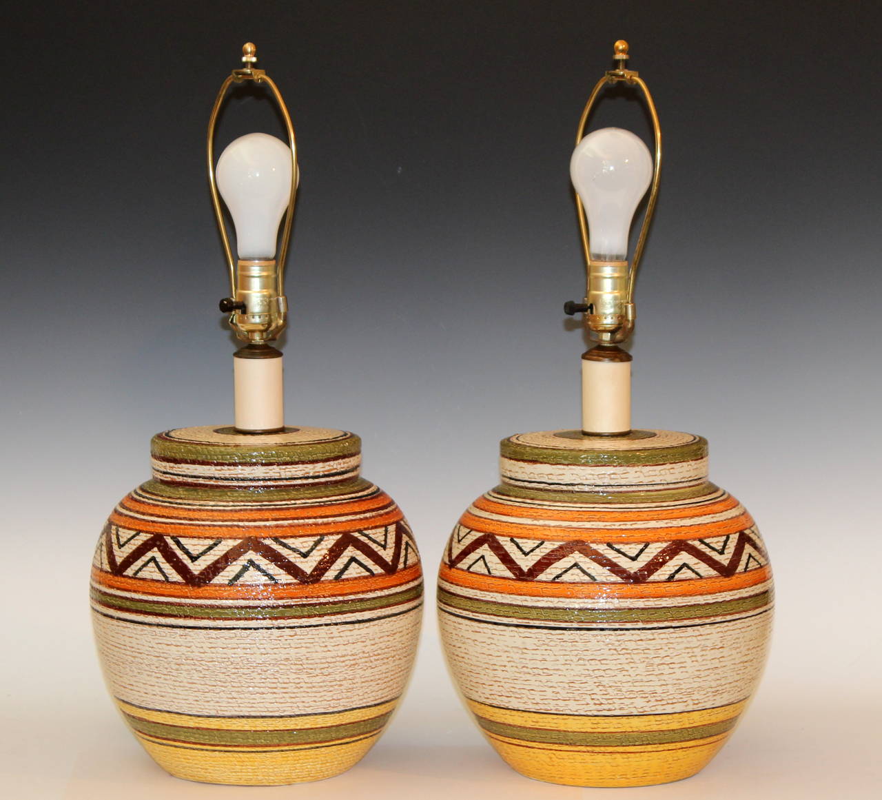 Large and heavy pair of hand-turned, vintage Bitossi lamps with earth colored glazes in geometric Navajo style tribal pattern over a basket weave ground, circa 1970s. Almost certainly made under the direction of Aldo Londi who had an affinity for