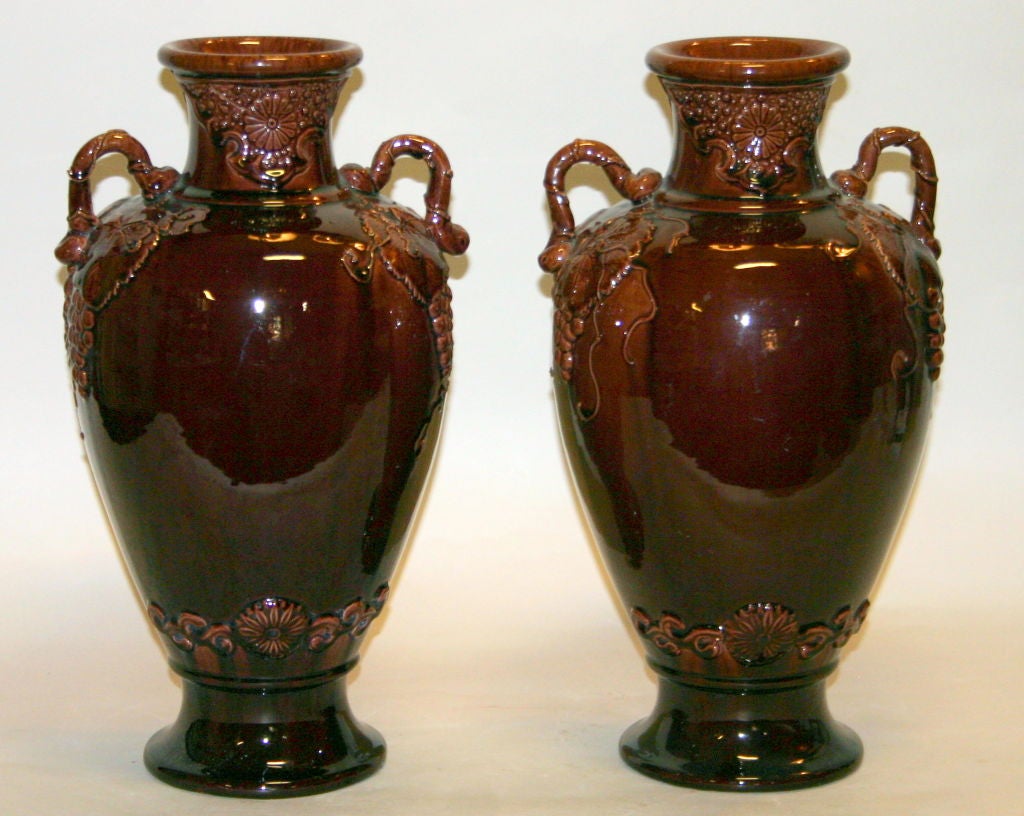 Large pair antique Kyoto pottery vases in rich aubergine glaze. Decorated with applied grape vines, chrysanthemum medallions, and applied grape vine handles, circa 1910. Excellent condition.