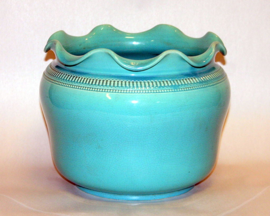 Antique hand thrown Wardle art pottery jardiniere with ruffled rim, slightly tucked waist, and great, machine tooled design on the shoulder. Covered in a soothing two tone aqua monochrome glaze. Impressed 