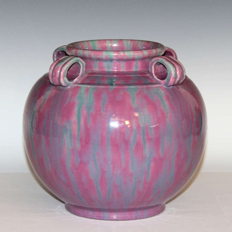 Large Awaji vase of globular form with articulated shoulder, rolled mouthrim, and four lug handles covered in blue streaked pink glaze. Impressed marks.
