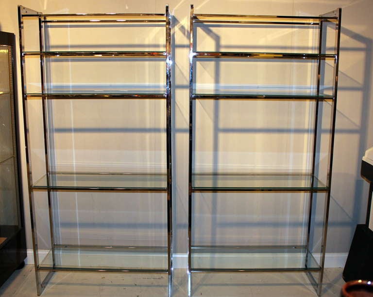 Pair vintage chrome etageres, circa 1970's, each with five glass shelves. There are foot pads on top and bottom so they can be inverted with either the smaller or larger shelves at the top.