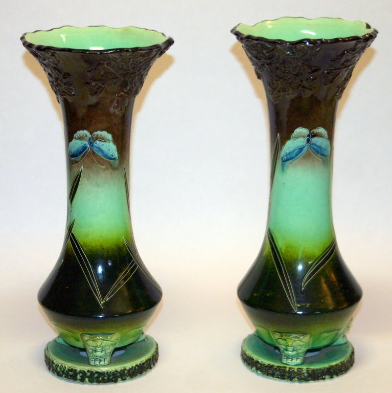 Pair Kyoto vases each decorated in squeezebag technique with irises and a butterfly against a dark ground as if dusk has fallen. Slightly elevated above a circular foot by three demon masks.