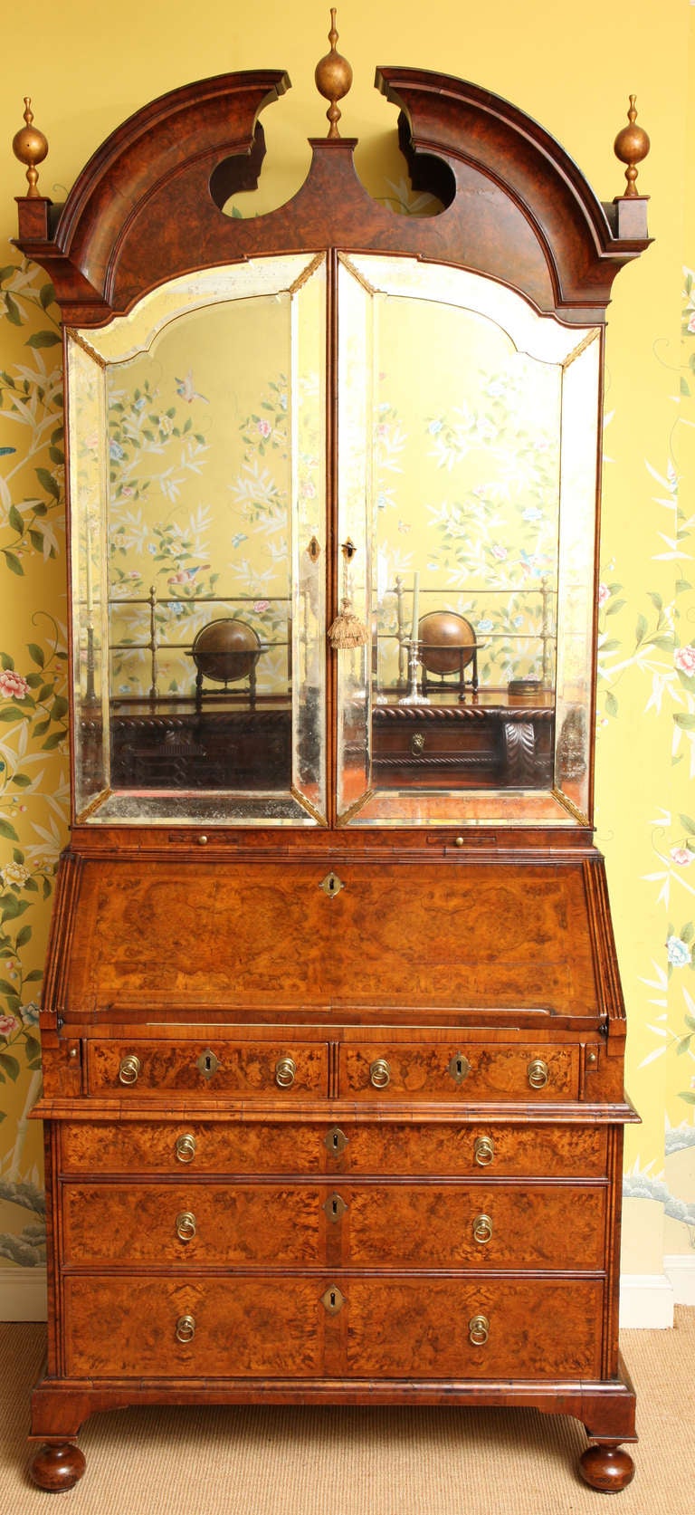 A Rare and Important Queen Anne Burl Walnut Bureau Bookcase, in three sections. The upper section having a molded broken arched pedimen with gilt finials, above a pair of arched beveled mirror doors with beveled mirrored border glass frames,  The