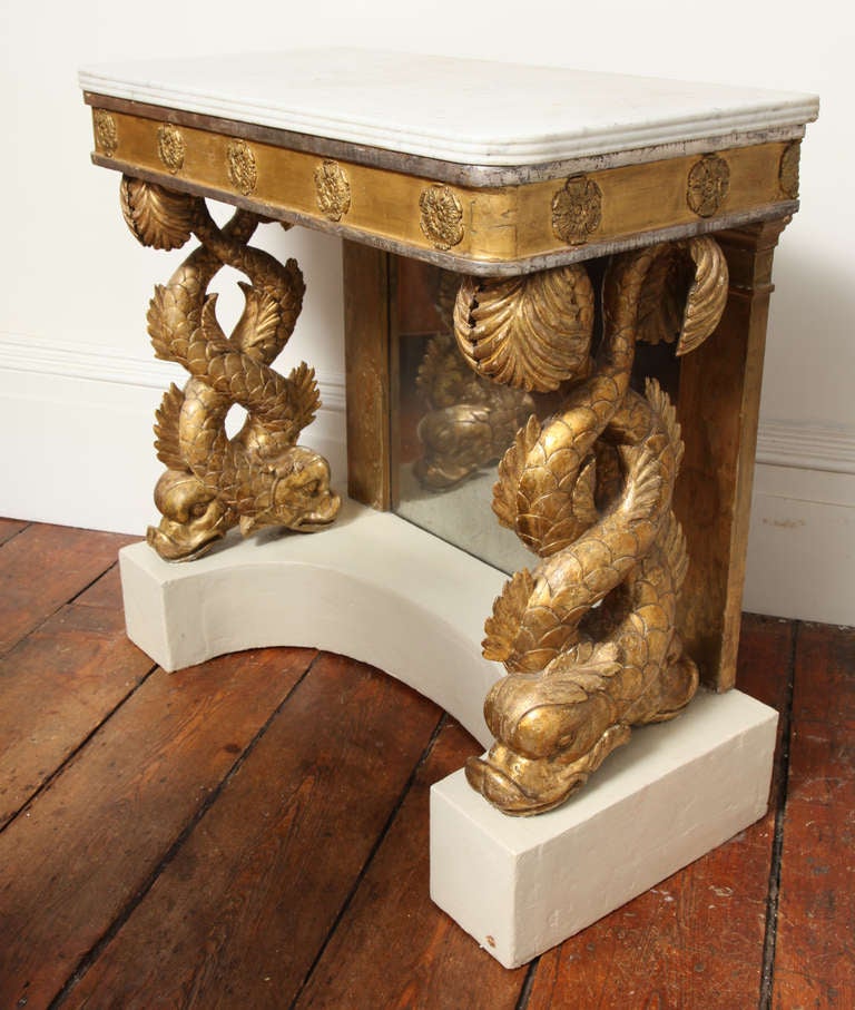 Fine Carved Giltwood and Silvered  Dolphin Console Table, retaining the original mottled white marble top with reeded edge, above twin intertwiningcarved and gilt  dolphin supports, with original mirrored back and white painted incurvate plinth