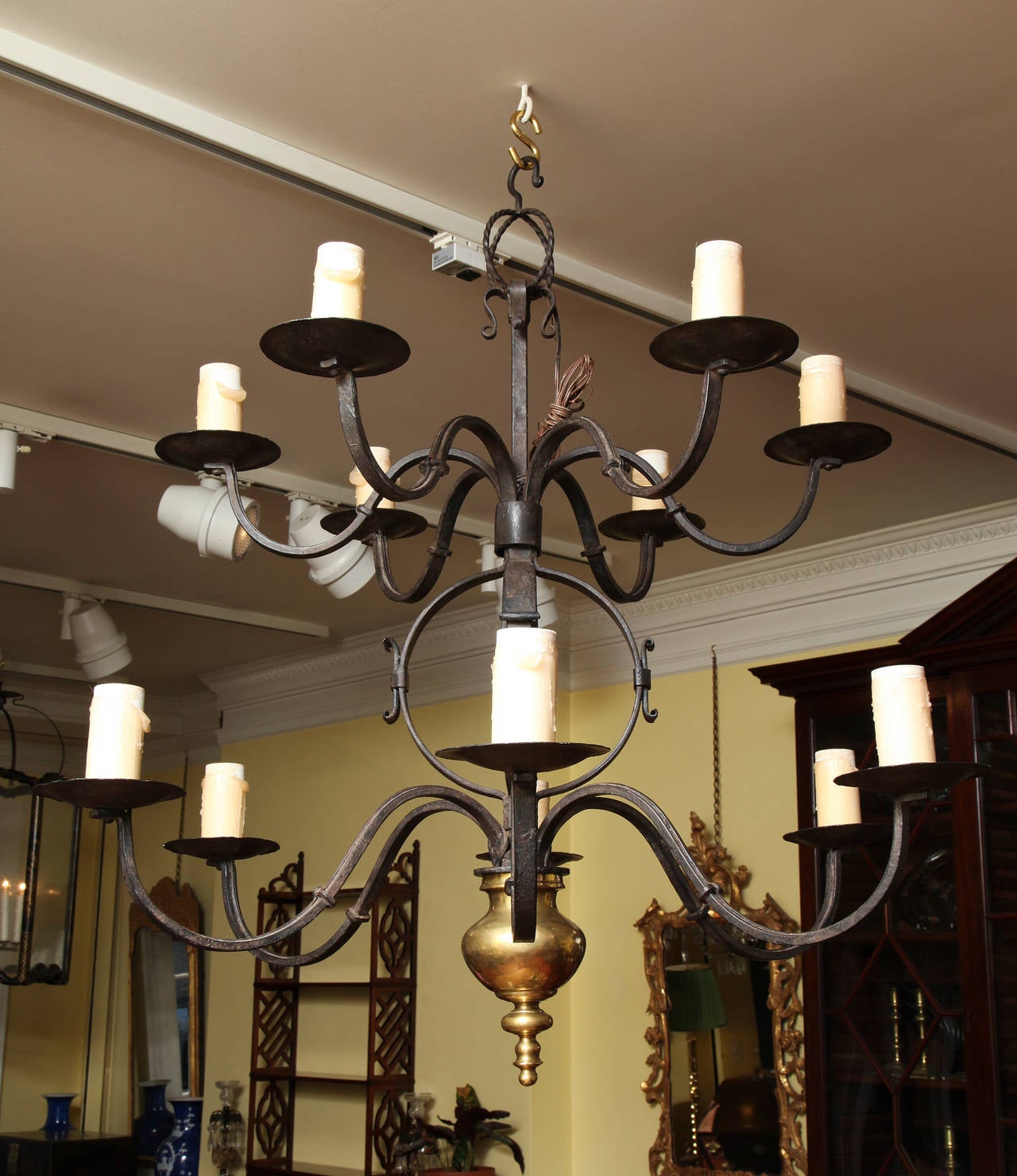 Fine two-tier hand-forged iron and brass twelve-light chandelier, having a scrolled top hook above a small twisted iron open sphere with four small C-scrolls and two graduated tiers of six serpentine knobbed arms with circular dished candle cups