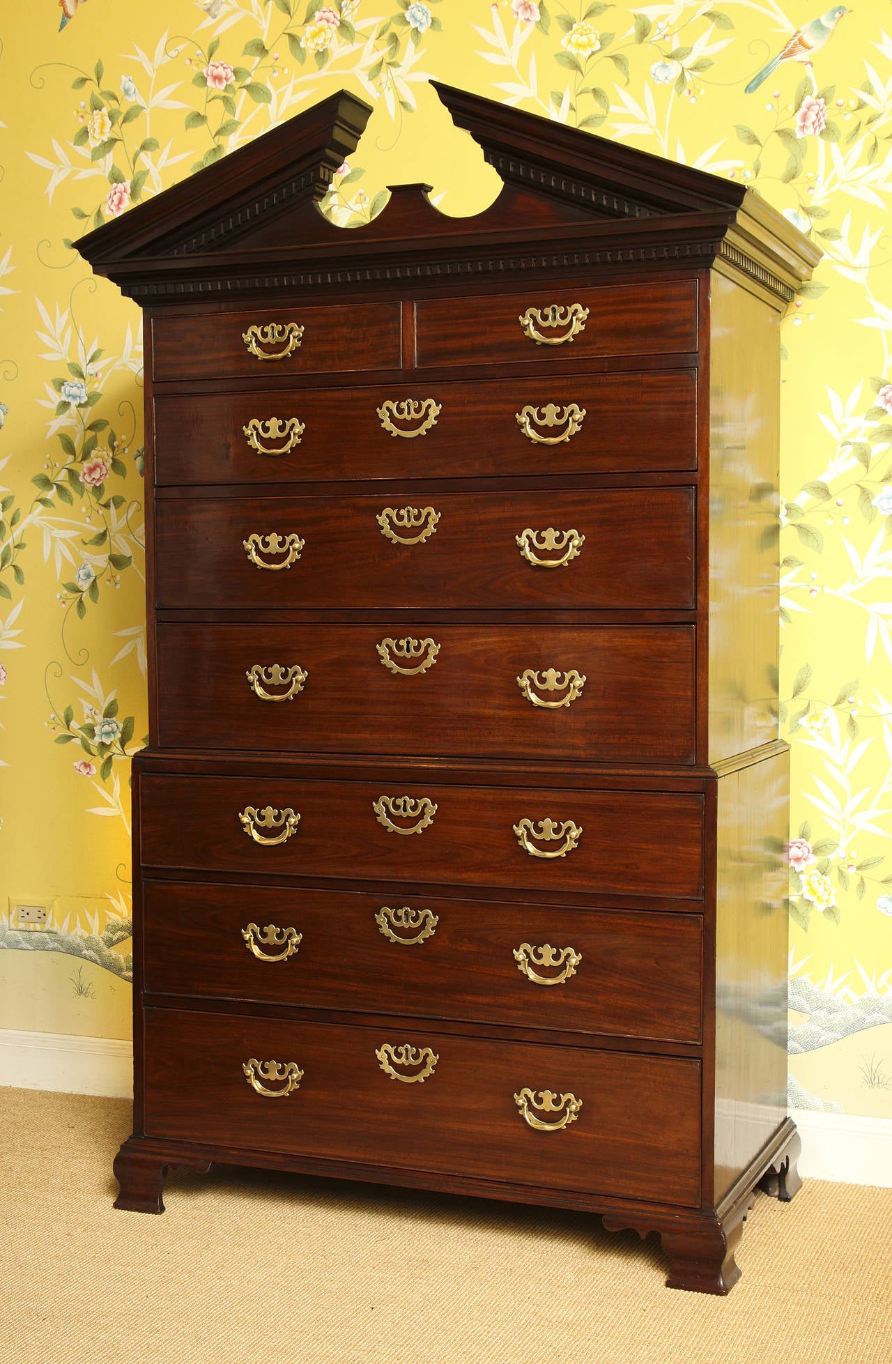 Very fine small-scale Chippendale period mahogany chest on chest, having a broken architectural pediment with two rows of dentil carving, the top section with two short and three long graduated cockbeaded drawers, the lower section with three long