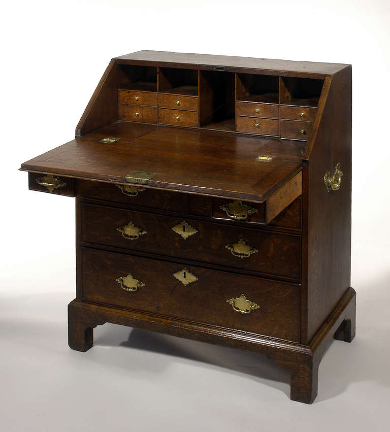 Fine George II walnut-inlaid oak slant-front bureau, the hinged front opening to reveal a writing surface and fitted interior with pigeon holes, small drawers and a sliding panel opening to a well, above four short and two long graduated drawers on