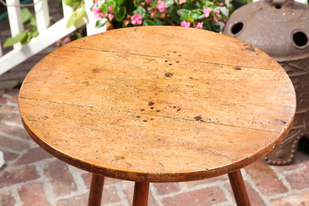 Circular Maple/Ash Cheese Board Table of wonderful color, with underlying solid elm slab support with nine dark contrasting pegs showing through to the top, on three splayed turned legs joined by a turned oak t-form stretcher. English or Welsh circa