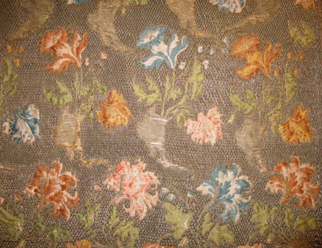 An unusual 18th century French brocaded cover with flowers in pale peach and blue colors and a heavy couched metallic ground.