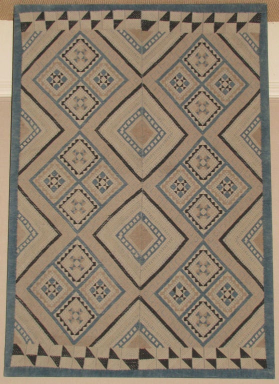 Early 20th century wedding blanket by Buyi minority group Guizhoi Prov., China embroidered in cotton with repeated patterns of squares with geometric centers in blue, beige and tan colors with an indigo dyed border. Mounted.