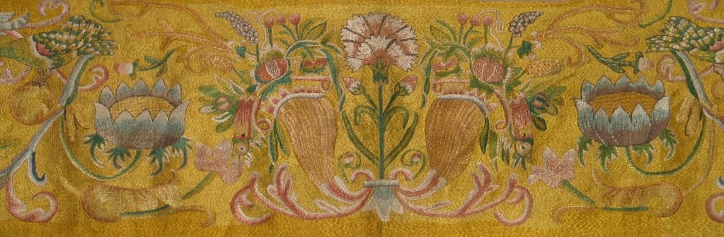 18th century Italian silk embroidered panel with an embroidered yellow ground embroidered with a central carnation flanked by horns of plenty filled with flowers; large flower heads, scrolling vines, and birds continue to  decorate the panel.