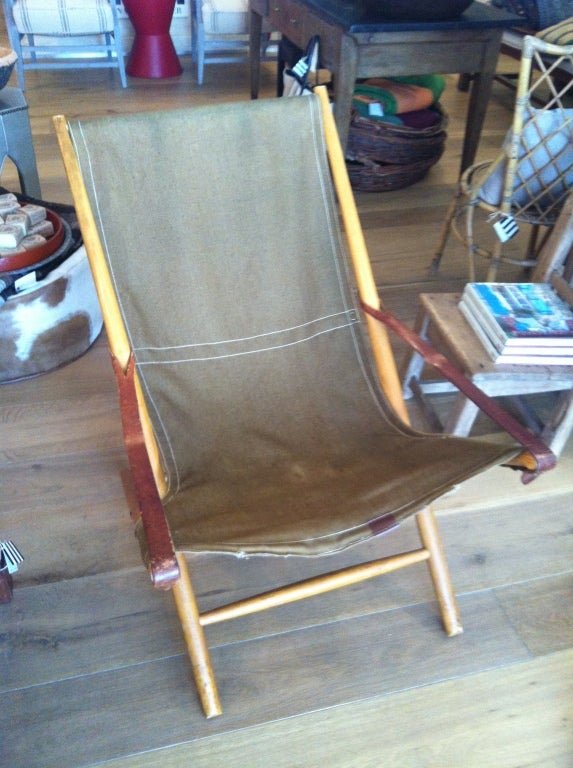 Beautiful wooden folding chair with woven seat and leather strap detail.