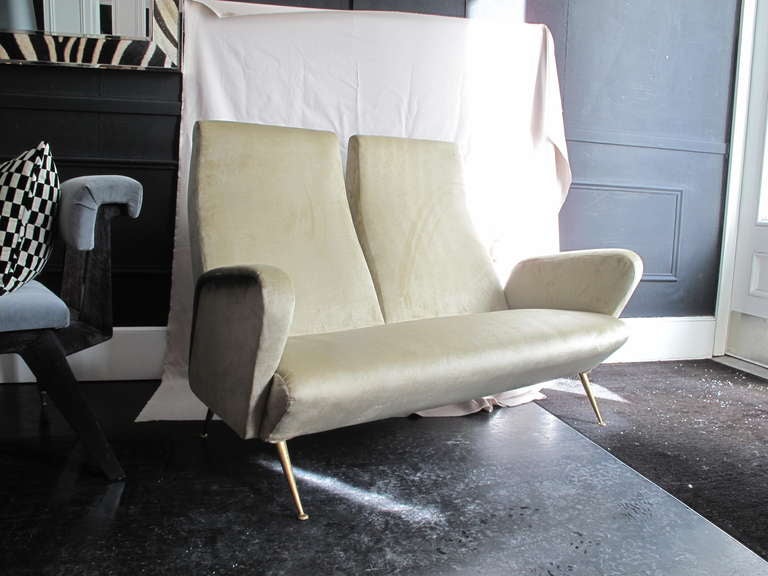 1950's Italian split back settee by Carlo de Carli, newly  reupholstered in champagne velvet on brass tapered legs.