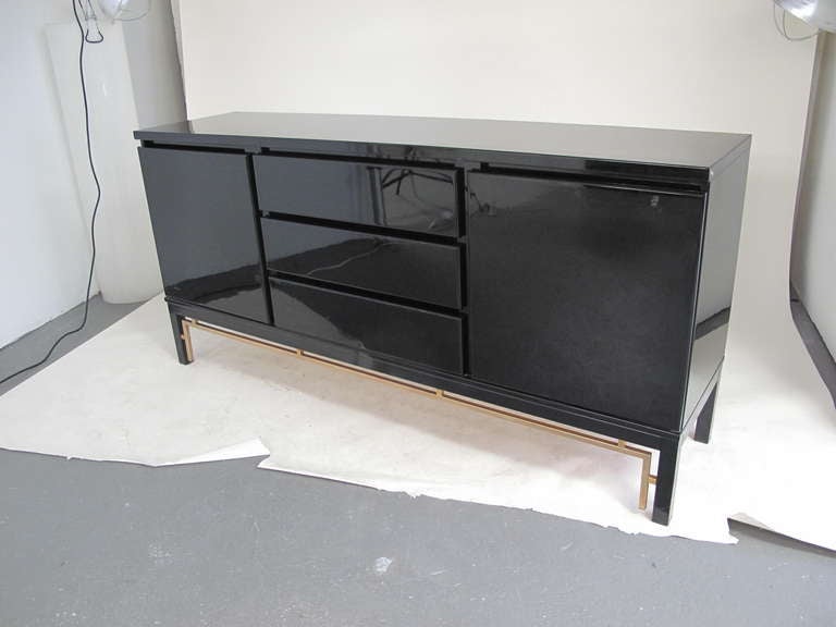 Vintage black lacquer sideboard with three drawers and two doors, with brass stretcher detail. France, 1970's.