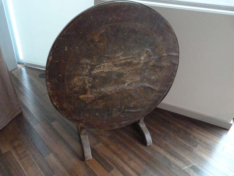 This wood table has heavily distressed leather top bound with metal band.