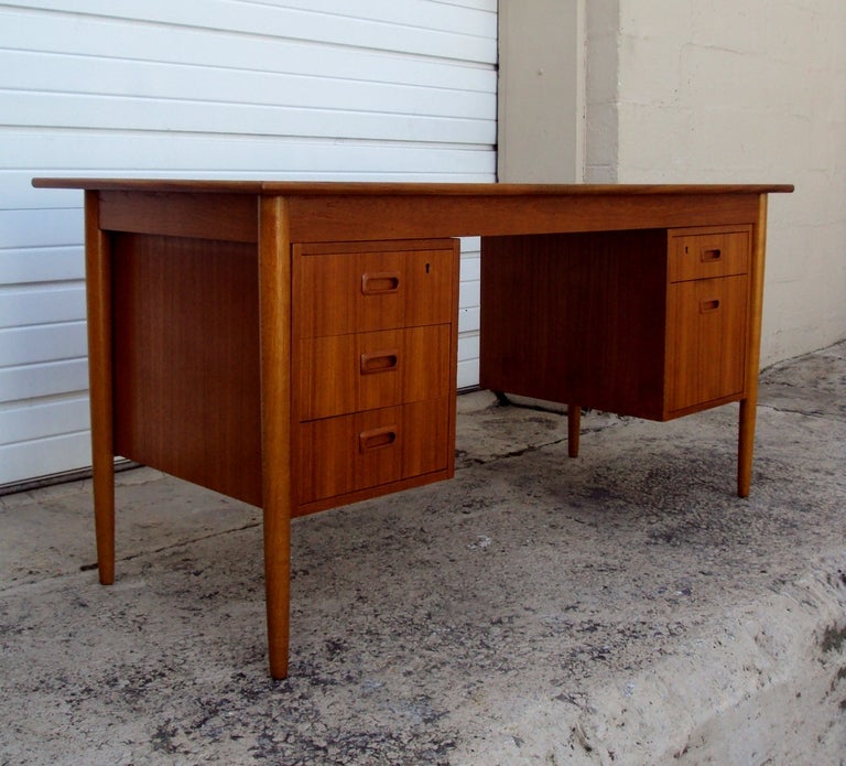 Spectacular Mid Century teak writing desk. Plenty of storage space in the five drawers (three on the left hand side and two on the right with one being a file drawer). The desk is finished on all sides and can therefore float in a room. This desk is