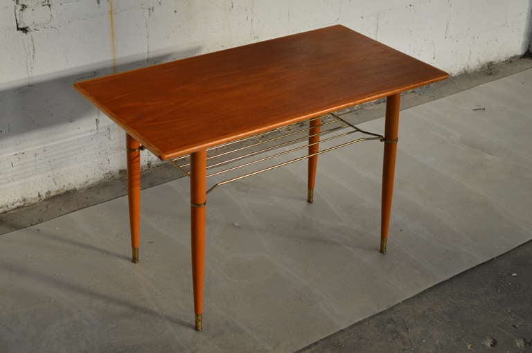 This petite Mid-Century Modern coffee table/side table was crafted in Sweden during the 1950's from solid teak wood. This simple streamlined design features a teak tabletop with a narrow teak skirt along the edges atop four tapered teak legs and a