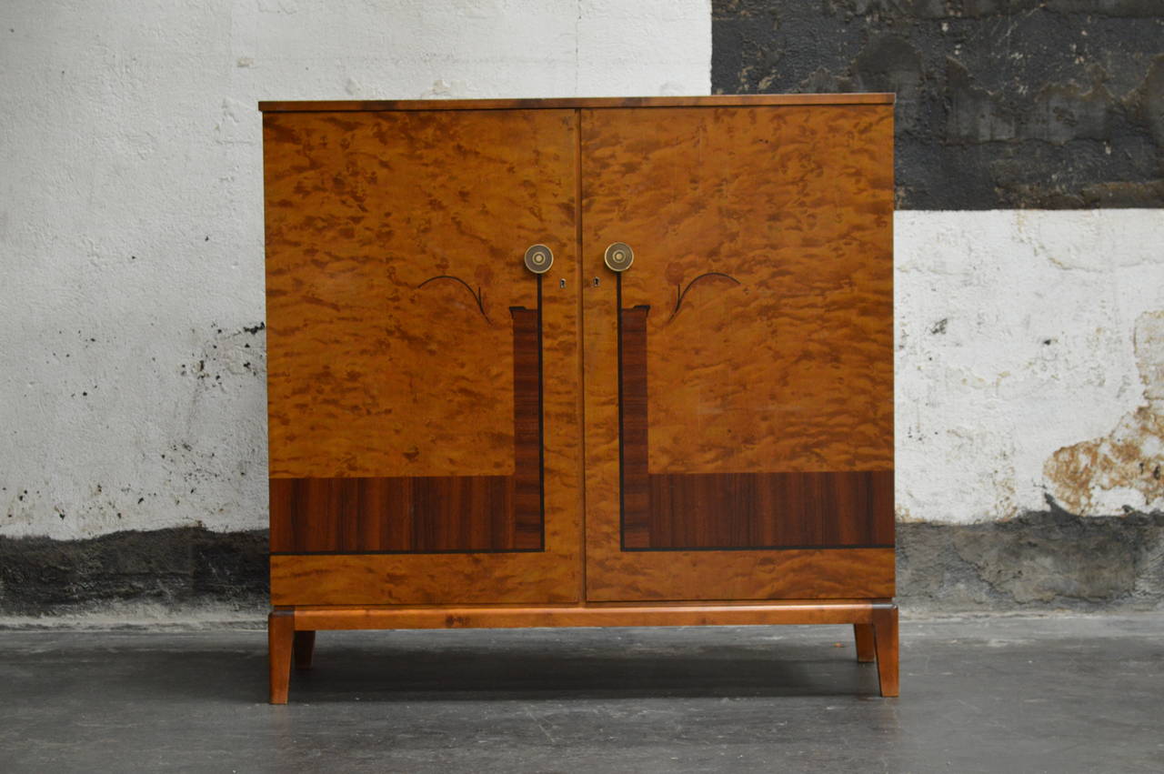 This Swedish Art Deco, verging on art moderne, storage/dining/bar cabinet belies that form follows function. In this case, they are considered equals! Crafted in golden flame birch, rosewood and a host of exotic hardwood inlays, this cabinet