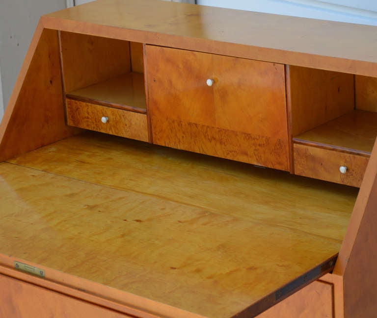 Uniquely sized drop-leaf secretary in sleek golden elm. Leaf folds down to reveal shelves, cubbyholes and three drawers of golden masurbjork (birch burl) and a drop-leaf desktop - just the right size for a notebook computer. Lower section features