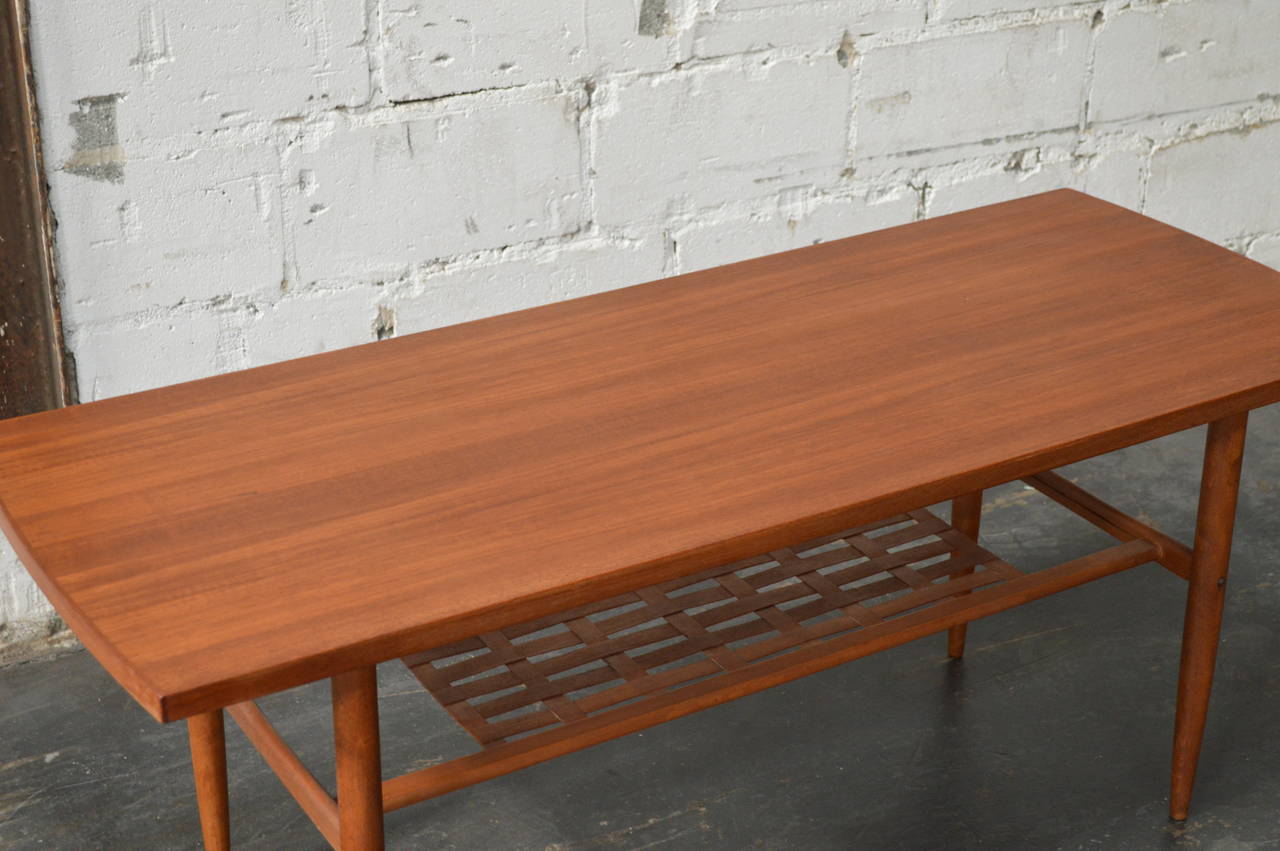 Midcentury Modern teak coffee table with shelf, Sweden circa 1960. Wonderfully clean and simple lines very nice design and craftsmanship quality piece. Turned tapered legs are a hallmark of mid-century design, as is the solid teak construction.