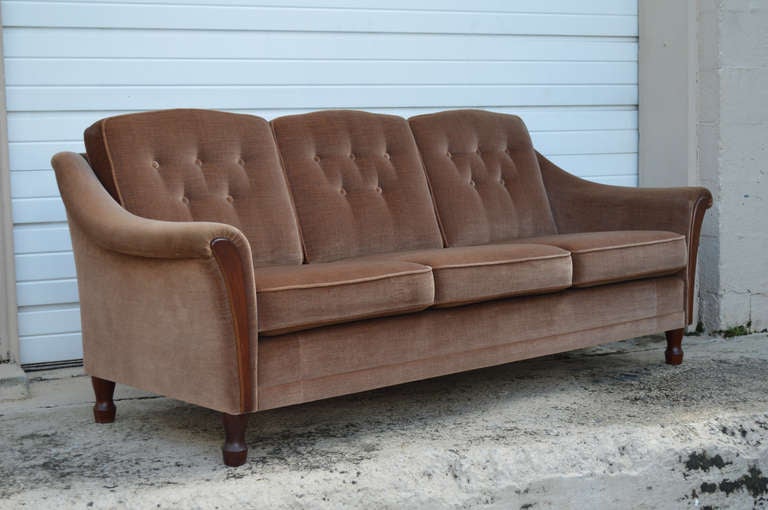 1970's three-seat sofa with dramatic flared arms with wood trim in original brown mohair wool velvet. The back cushions are button tufted which accentuates the original luminescent mohair velvet. The sofa can appear lighter or darker depending on