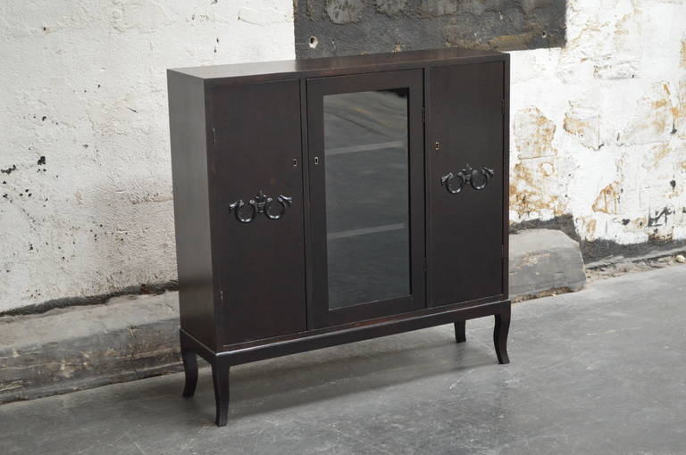 Gorgeous Swedish Neoclassical Revival dark flame birch three-door cabinet with three interior shelves in each. Ebonized medallion on both side doors and glass front middle door. Key included.

Additional dimensions:
Left and right doors 11 1/2