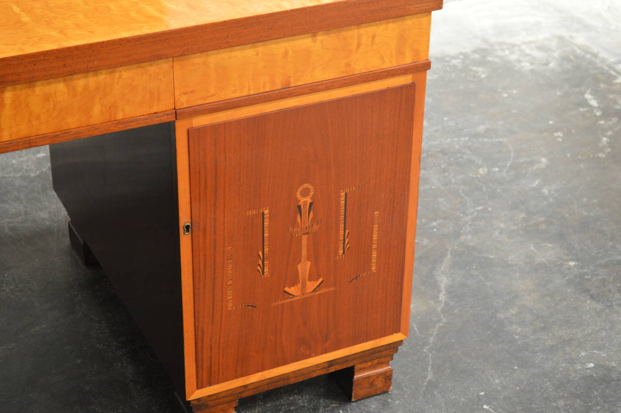 Swedish inlaid Art Deco or neoclassical executive desk, Sweden, circa 1930s. Exterior golden elm, flame birch, mahogany. The front two doors are paneled and inlaid with intarsia of ebonized birch, mahogany, elm and jacaranda wood. Interior in flame