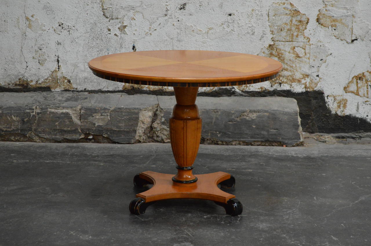 Swedish Art Deco round pedestal end or side table in golden elm. The table top is paneled and inlaid with intarsia of contrasting Swedish birch wood. Feet and details are made of ebonized birch. The Scandinavian deco table is the perfect size beside