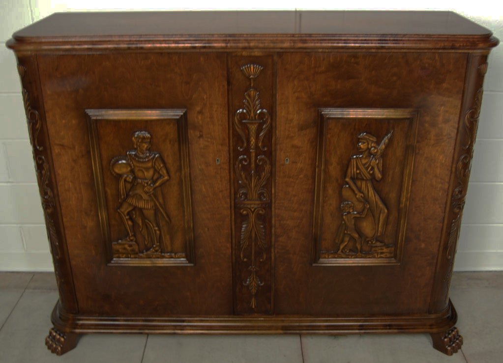 Large Neoclassical Revival / Art Deco carved buffet sideboard credenza cabinet of dark flame birch. Made in Sweden in the 1940's, this credenza has detailed relief carvings depicting a man, woman, and child as well as additional decorative elements.