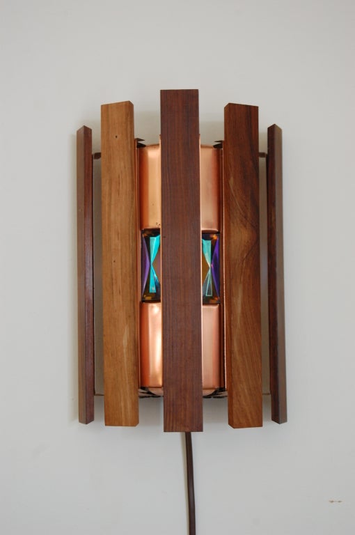 Swedish Mid-Century Modern MCM sconce designed by Werner Schou for Coronell Elektro. Sconce is made of jacaranda wood slats, copper, and inset with multicolor faceted glass. This unique wall lamp would complement a variety of design styles in