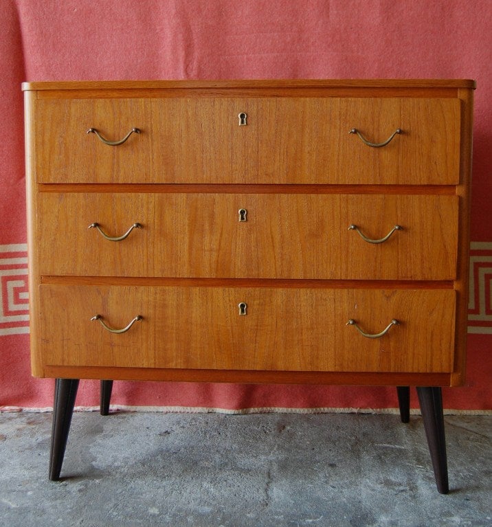 Three drawer teak chest on round dark brown/espresso tapered legs.