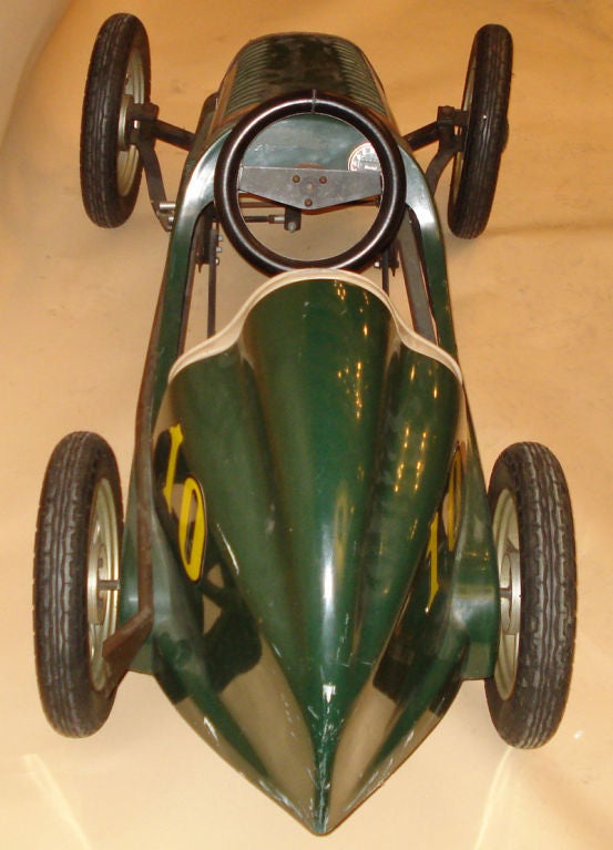Pedal Car with leather interior, and leather hood straps. British Racing Green painted exterior w/ chrome grill & mag wheels. Decorated with the number 10, and the Union Jack (British Flag) on the side. Enamel GT medallion on the grill, and boat