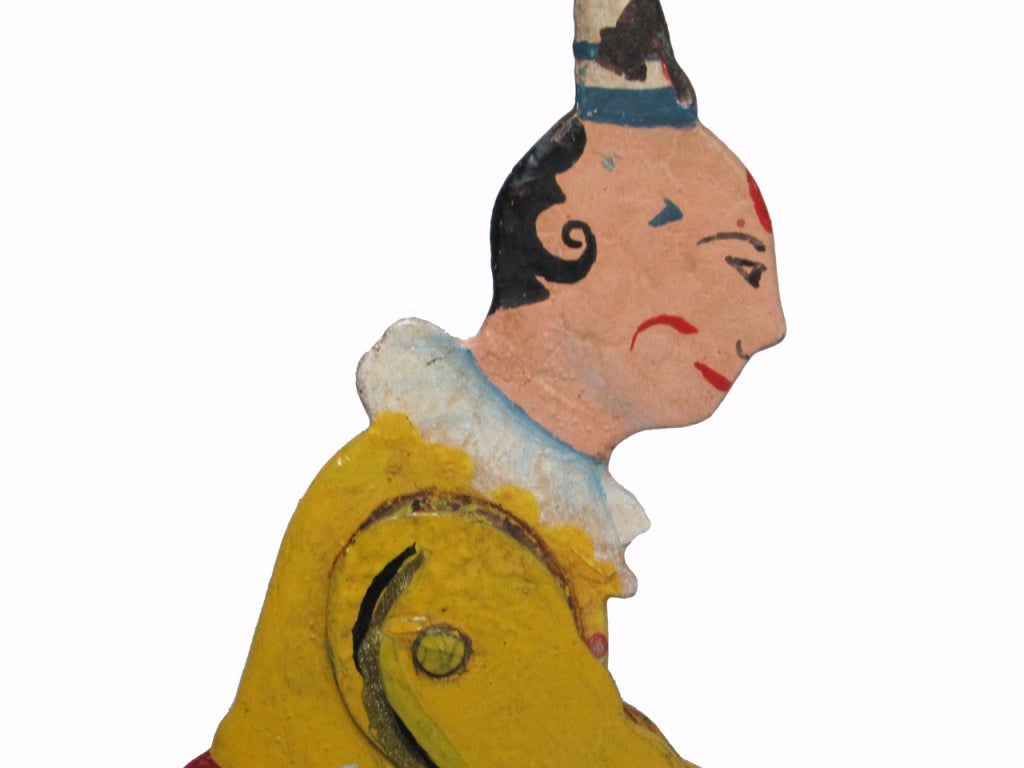 Circa 1930 double sided metal pull toy of a rodeo clown sitting on a bull with articulated arms and legs that move when the wheels turn, all in multi colored original paint
