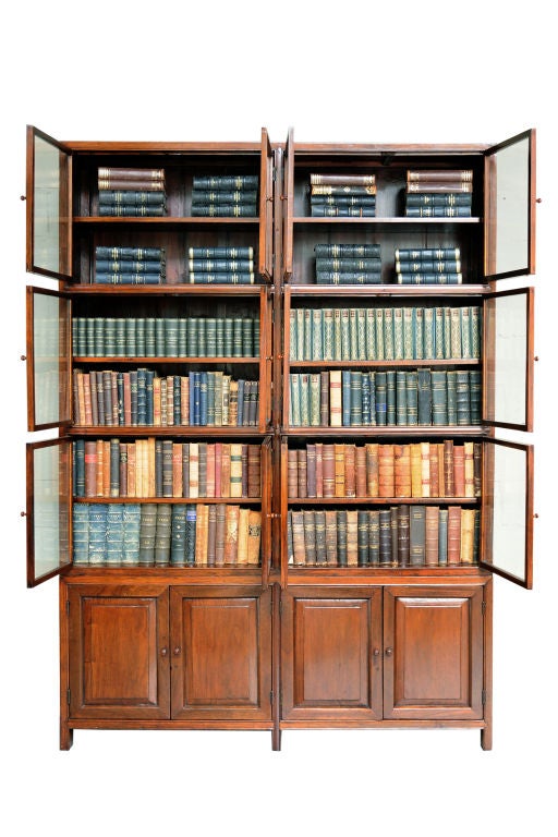 A Spanish Colonial Narra wood bookcase cabinet, Circa 1900, in two parts: the top section with glazed doors above, the lower section with cupboard doors.