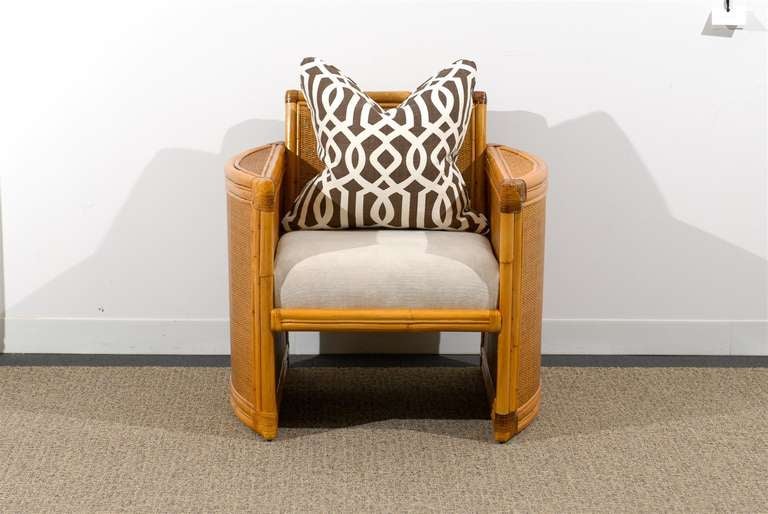 A stunning pair of lounge or club chairs, circa 1970. An unusually beautiful design executed in rattan and hardwood; veneered in raffia and aged to absolute perfection. Handsome leather detailing add accent. Comfortable and exquisitely made pieces